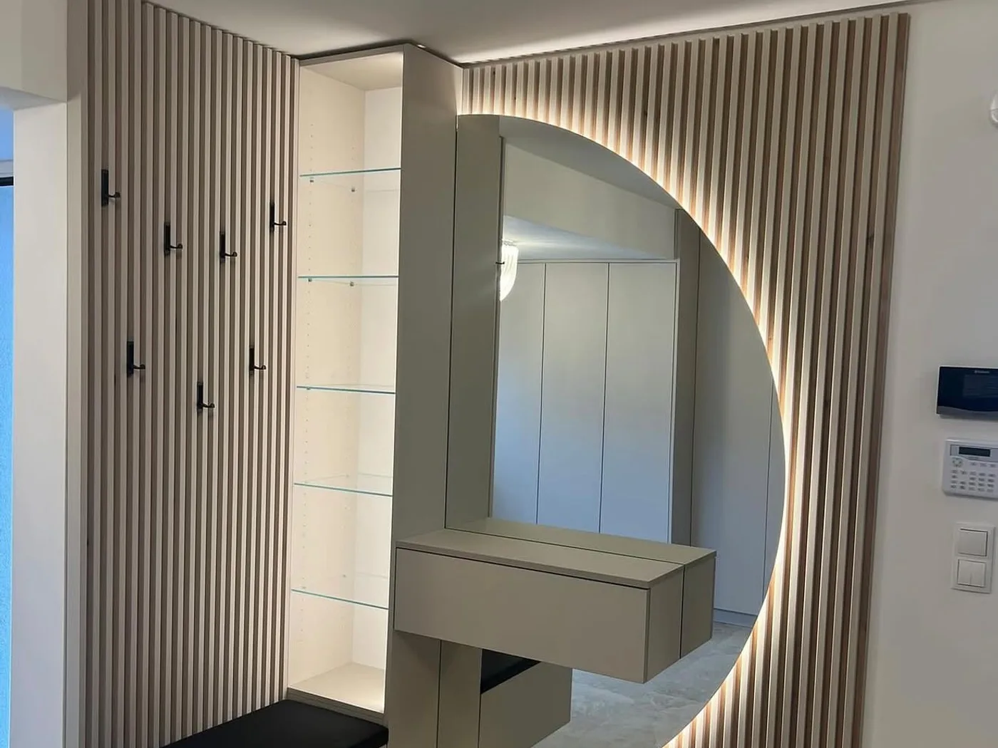 Hallway with slatted wall and backlit round mirror