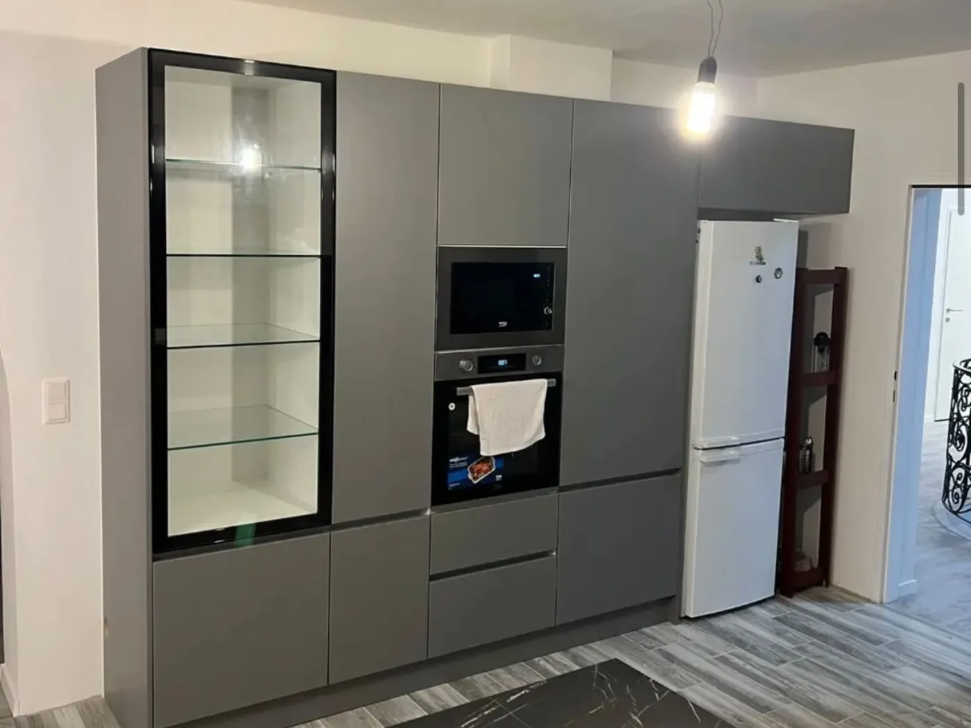 Graue Hochschrankwand mit Glasvitrine, Backofen und Mikrowelle