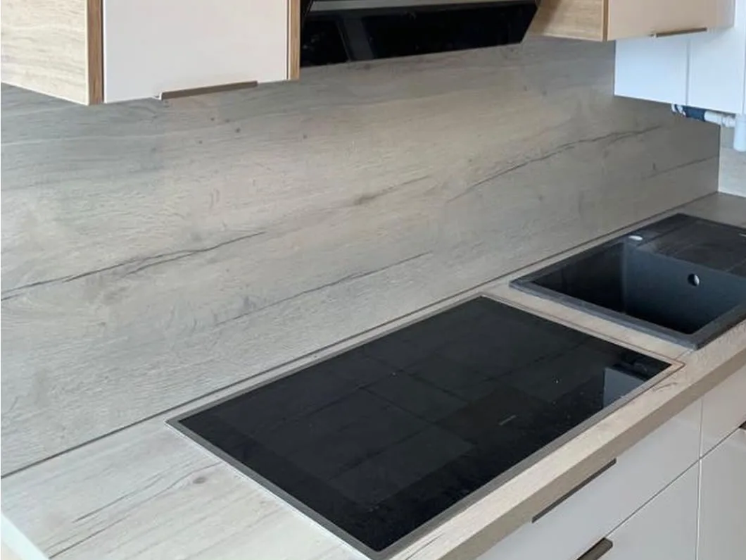 Kochfeld und Spüle vor einer Rückwand in heller Holzoptik